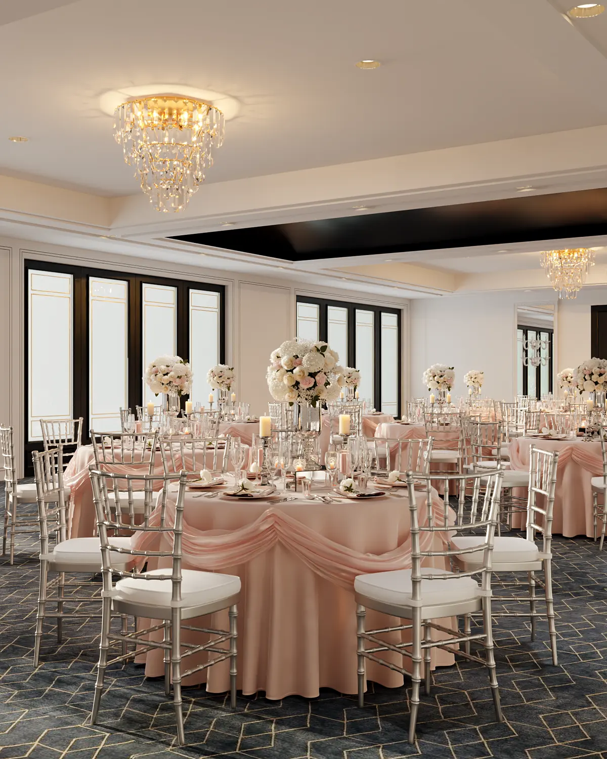 Banquet hall set for an event with round tables, blush linens and crystal chandeliers