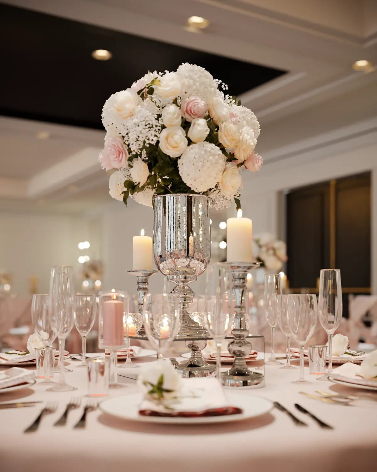 Banquet table setting with a tall white floral centrepiece and crystal glassware