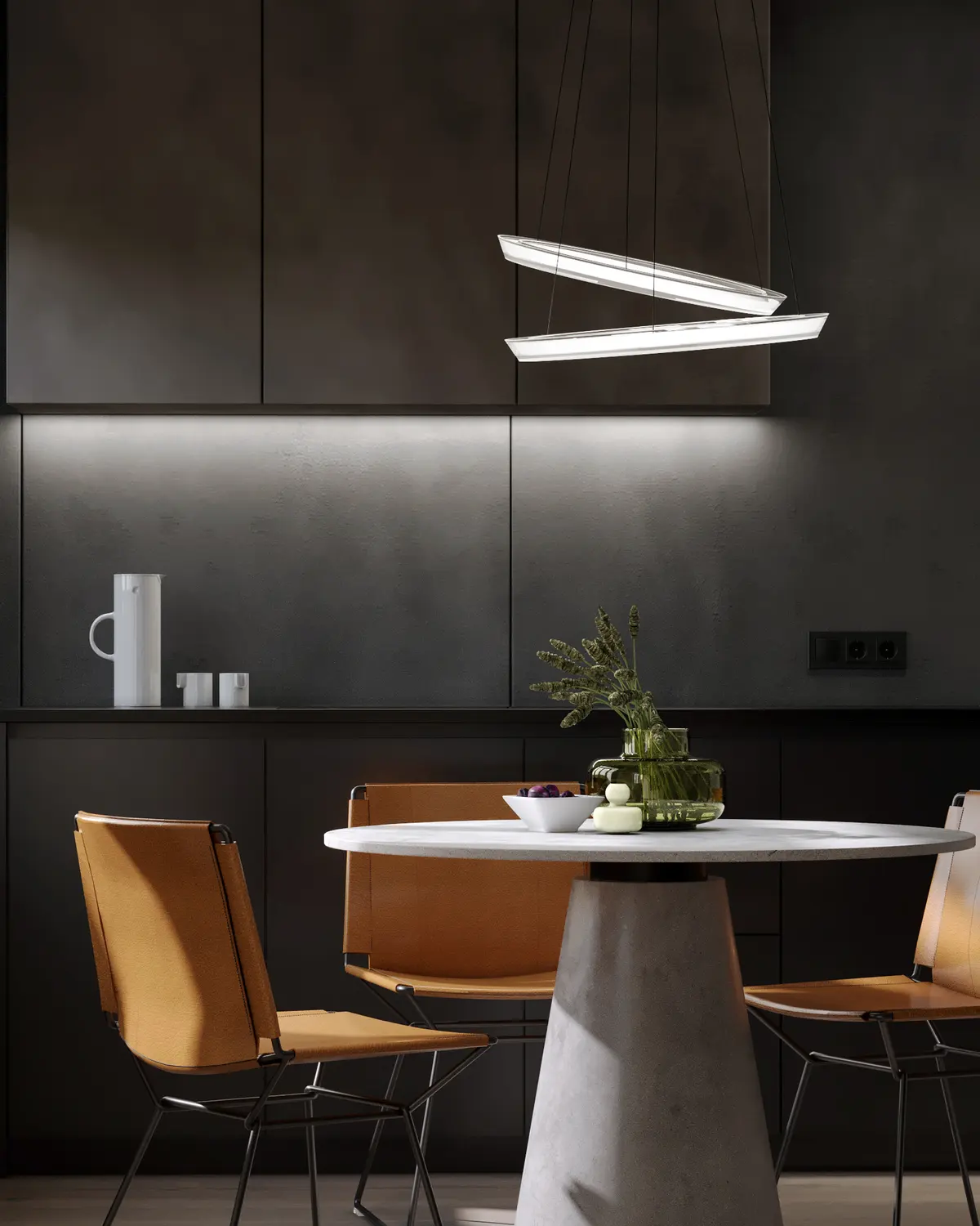 Dark matte kitchen with a round dining table, tan leather chairs and a linear pendant