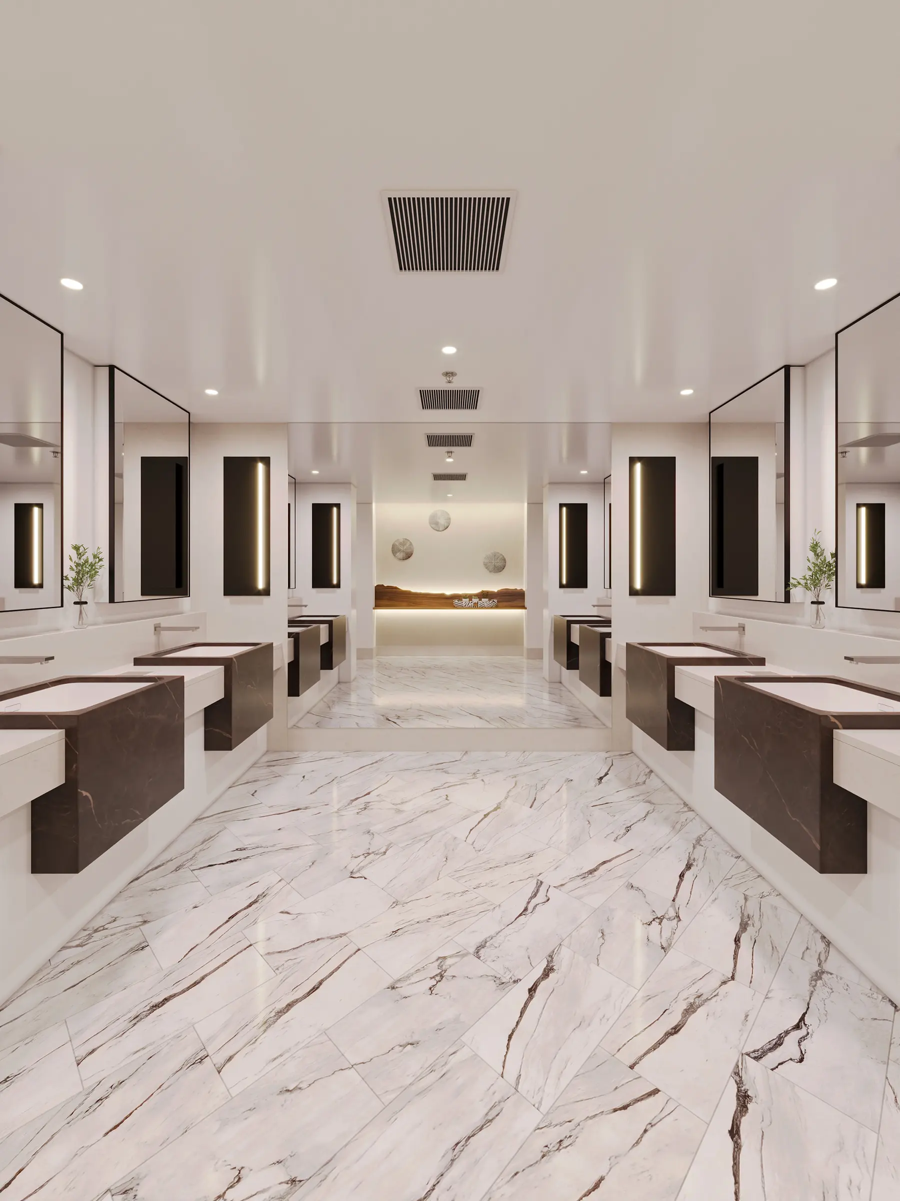 Public washroom with marble flooring and mirrored vanities along a symmetrical corridor
