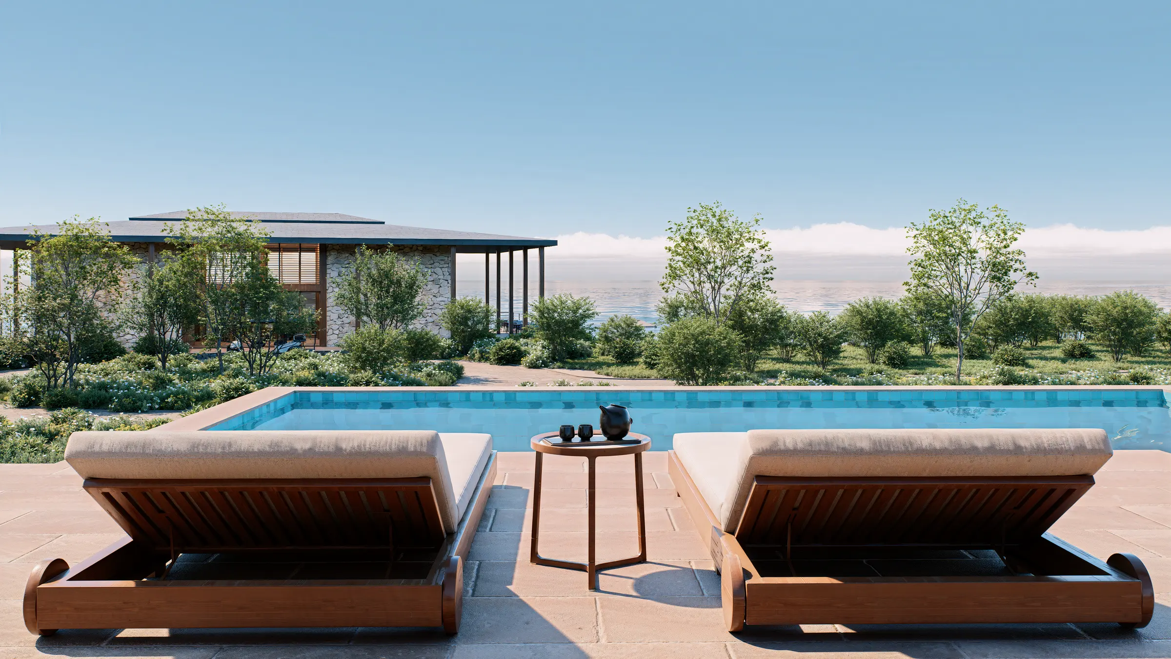 Pool deck daybeds at eye level, looking across the pool towards the sea